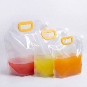Three clear plastic spout pouches with yellow handles filled with red, yellow, and orange liquid against a clean white background.